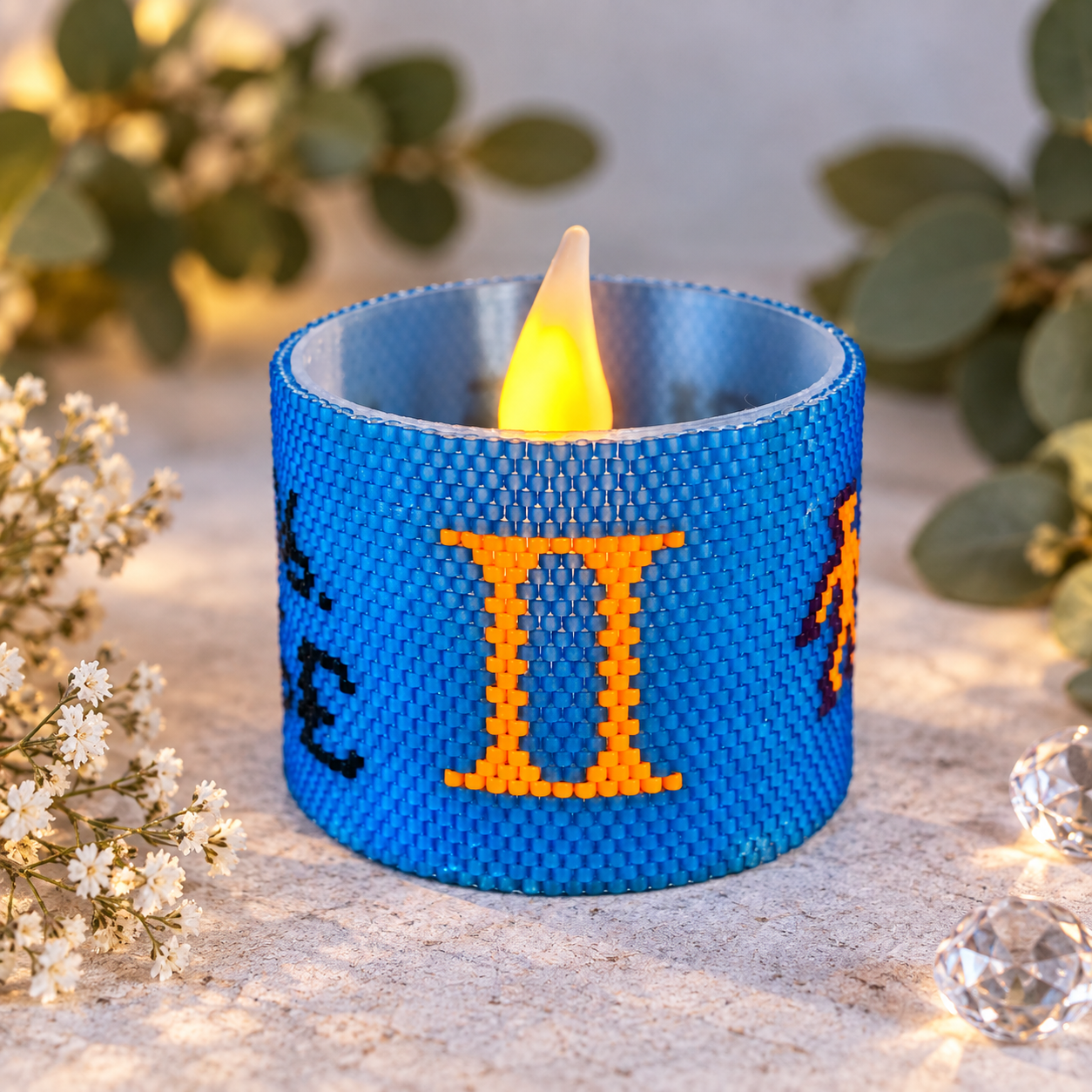 Windlichtumrandung Zwillinge aus blauen Perlen mit orangefarbenem Sternzeichen-Symbol und LED-Teelicht